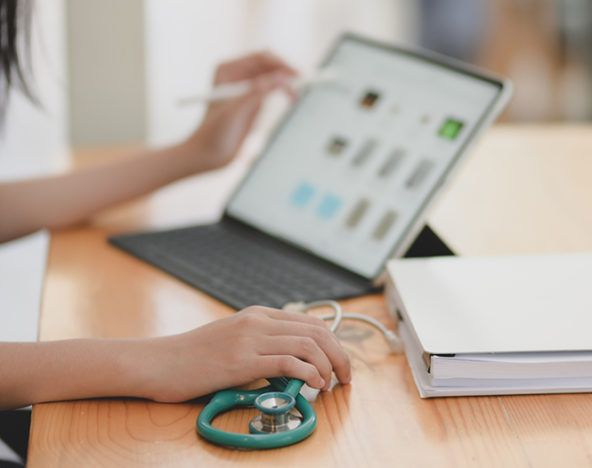 A nurse is utilizing a laptop and a stethoscope.