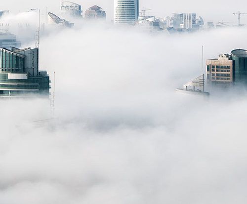 An aerial view of a city enveloped in clouds.