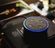 An echo dot sits on top of a book in a home office.