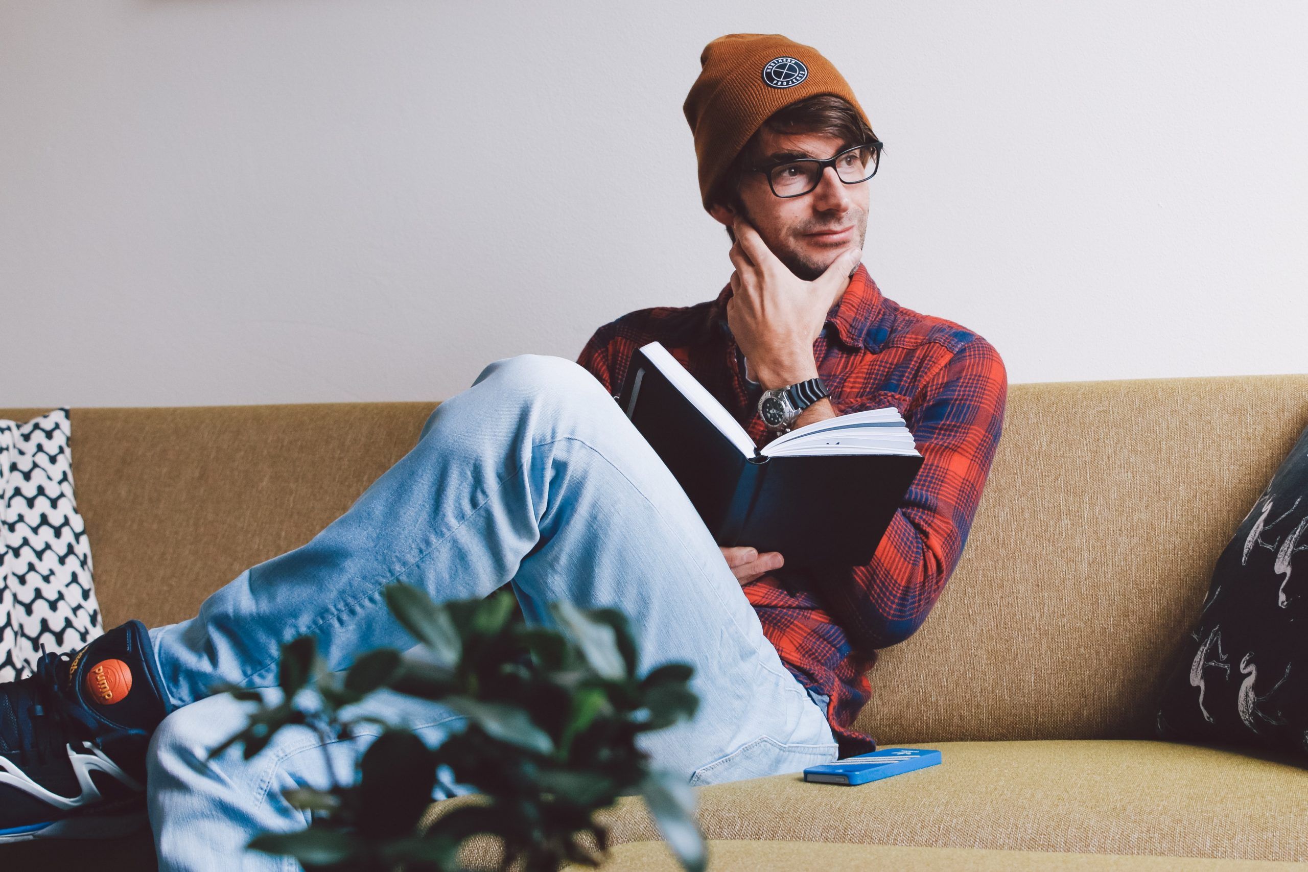 A man sitting on a couch reading a book.