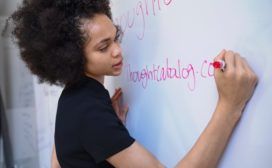 A woman working in her home office, writing on a whiteboard.