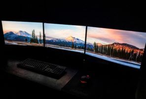 Three monitors are set up in a dark room to support a cloud strategy.