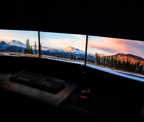 Three monitors are set up in a dark room to support a cloud strategy.