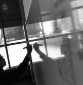 A monochromatic image of a man jotting down notes on a whiteboard.