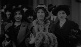Three women in hats standing in front of a crowd.