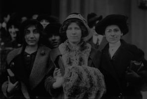 Three women in hats standing in front of a crowd.