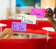 Two people holding up sticky notes that say done to do, showcasing the efficient use of technology in managing tasks.