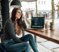 A woman engrossed in a laptop at a table.