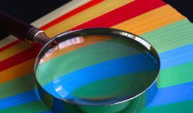 A magnifying glass testing a stack of colored paper.