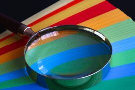 A magnifying glass testing a stack of colored paper.