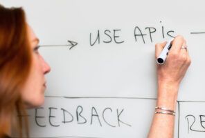 A woman writing on a whiteboard with the words API Integration.