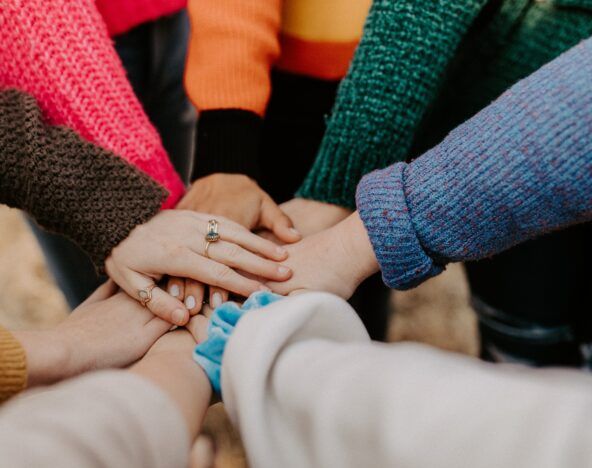 A group of people sharing knowledge, putting their hands together in a circle.