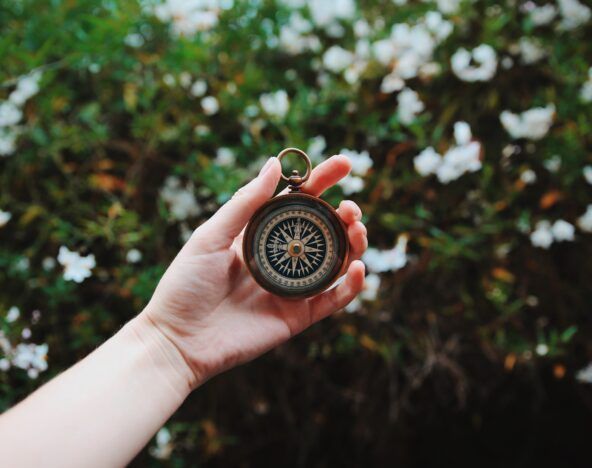 A person sharing knowledge while holding a compass in front of flowers.