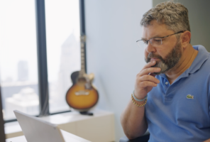 Man working with a guitar in the background