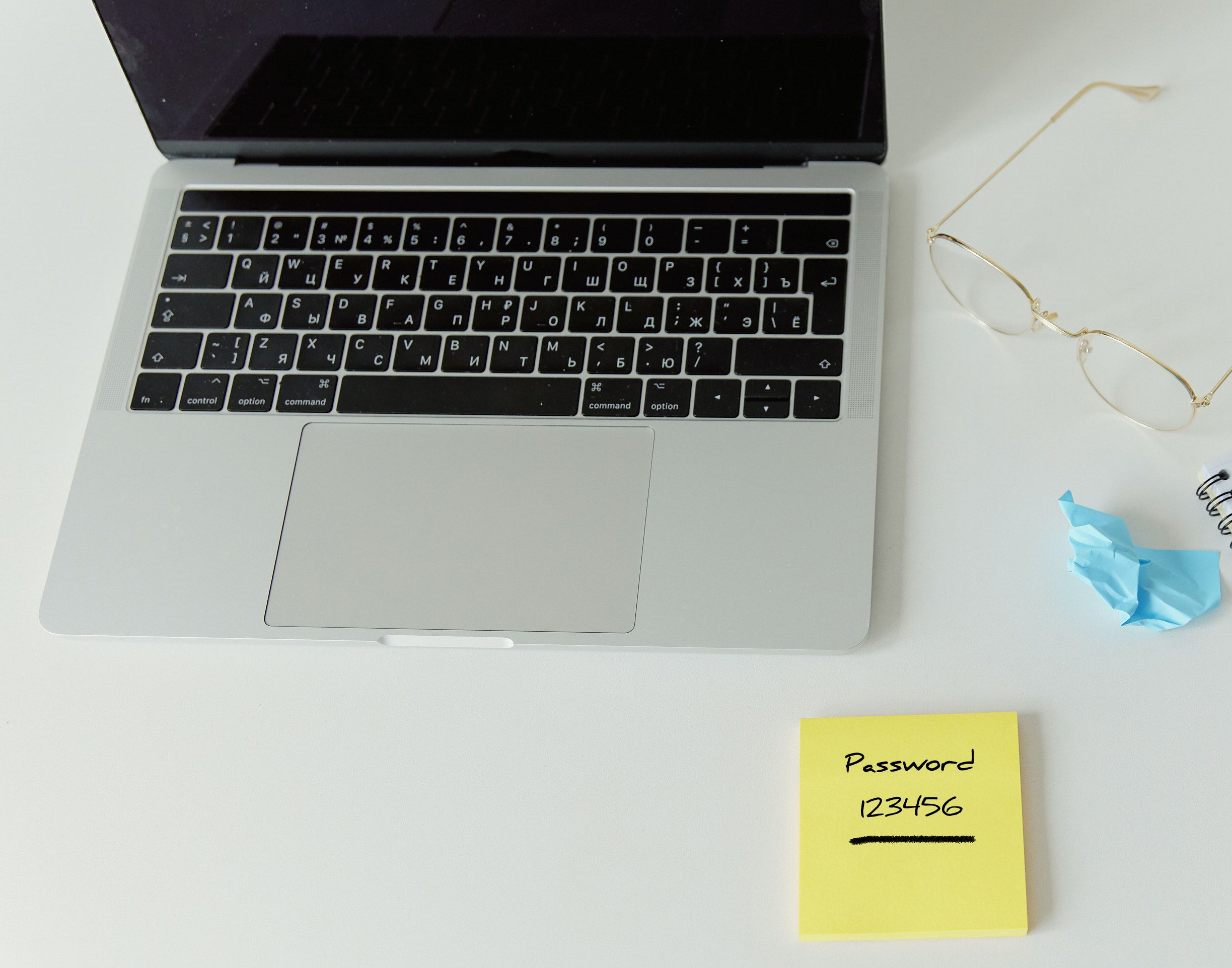 Password on a sticky note next to a laptop