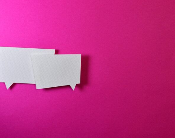 Two paper speech bubbles discussing DevOps challenges on a pink background.