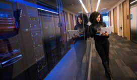 Woman with a laptop walks between servers