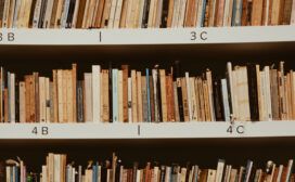 Books lined up on library shelves marked with labels 3B, 3C, 4B, and 4C display a variety of colors and thicknesses, holding within them stories and insights into technology predictions for the future.