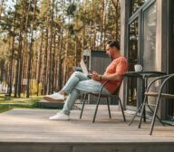 Work from home. A young man with a laptop sitting outside and working online