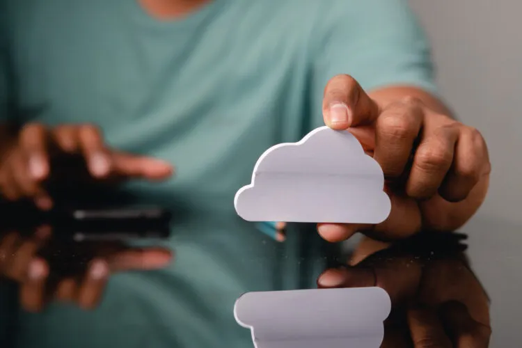Person holding a cloud-shaped cutout with a reflection on a surface.