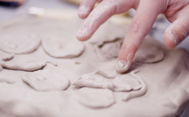 Close-up of a hand shaping clay into hearts on a modernized work surface.