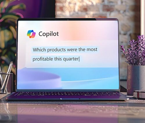 A laptop on a desk displays the Microsoft Copilot application with the prompt "Which products were the most profitable this quarter?" The desk has plants, a coffee mug, and a notebook.