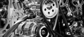 Close-up of a complex engine with visible pulleys, belts, and metal components in black and white.