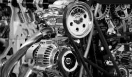 Close-up of a complex engine with visible pulleys, belts, and metal components in black and white.