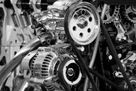 Close-up of a complex engine with visible pulleys, belts, and metal components in black and white.
