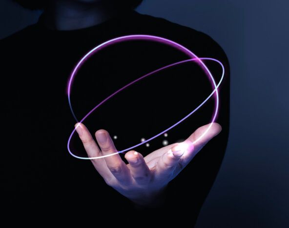 A hand emerges from the shadows, gripping glowing, intersecting purple rings against a dark background—a glimpse into the world of 2025 tech predictions.