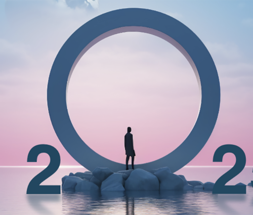 A person stands on rocks in front of a large ring between the numbers 2025, symbolizing the dawn of tech predictions, set against a pink and blue sky over water.