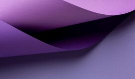 Curved sheets of purple paper overlap each other on a flat, light purple surface.