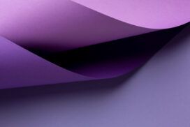 Curved sheets of purple paper overlap each other on a flat, light purple surface.