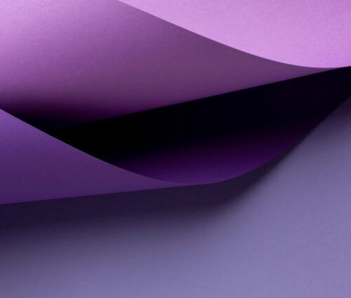 Curved sheets of purple paper overlap each other on a flat, light purple surface.