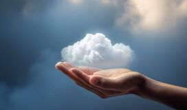 A hand is held out with a small, fluffy white cloud hovering above the palm, evoking the concept of cloud migration against a soft blue and cloudy background.