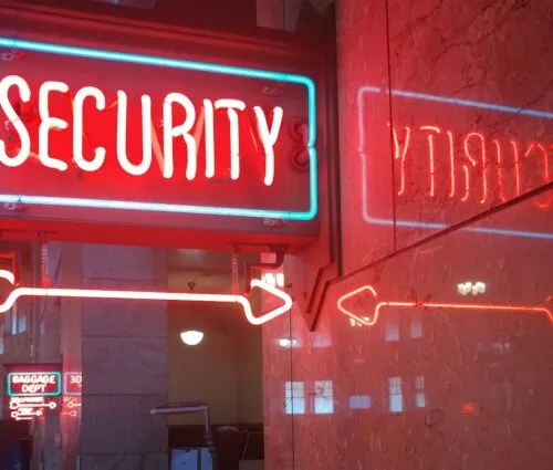 A red neon sign reading "SECURITY" with arrows, symbolizing enterprise AI security, is reflected on a marble wall. In the background, another neon sign reads "BAGGAGE DEPT.