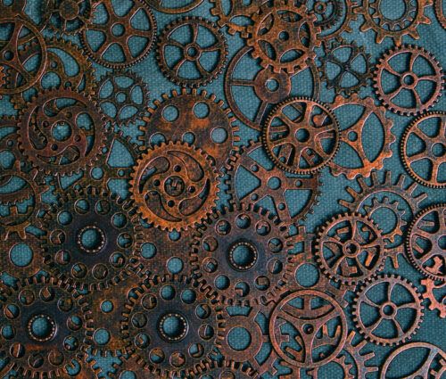 A collection of variously sized, rusty metal gears and cogs arranged closely together on a textured blue surface, evoking the intricate mechanics behind AI agent development lessons.