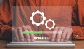 Person wearing an orange shirt typing on a keyboard, with a transparent graphic overlay showing gears and a progress bar labeled "UPDATING...