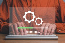 Person wearing an orange shirt typing on a keyboard, with a transparent graphic overlay showing gears and a progress bar labeled "UPDATING...
