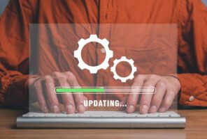 Person wearing an orange shirt typing on a keyboard, with a transparent graphic overlay showing gears and a progress bar labeled "UPDATING...