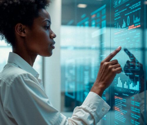 A person in business attire interacts with data visualizations on a large transparent touchscreen in a modern office setting.