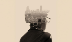 A person wearing glasses is seen from behind, with a cityscape superimposed within the silhouette of their head and shoulders.