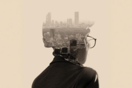 A person wearing glasses is seen from behind, with a cityscape superimposed within the silhouette of their head and shoulders.
